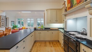 Una cocina amplia con una isla grande, piso de madera y electrodomésticos modernos.