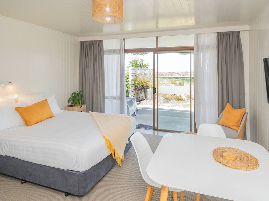 A modern hotel room with a bed, a dining table, and a TV.