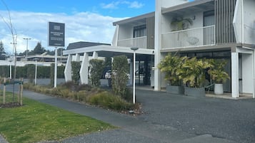 Un hotel moderno con techo plano, balcón y un cartel que indica habitaciones disponibles.