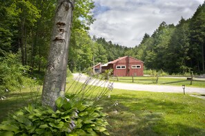 Une grange rouge se trouve dans une zone boisée, et un chemin de terre mène à celle-ci.