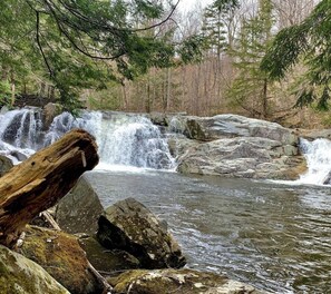 A natural waterfall surrounded by rocks and trees.