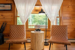 A room with two leather chairs, a small wooden table with a book and binoculars, and a flag on the wall.