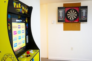 Une borne d’arcade Pac-Man et un jeu de fléchettes fixé au mur.