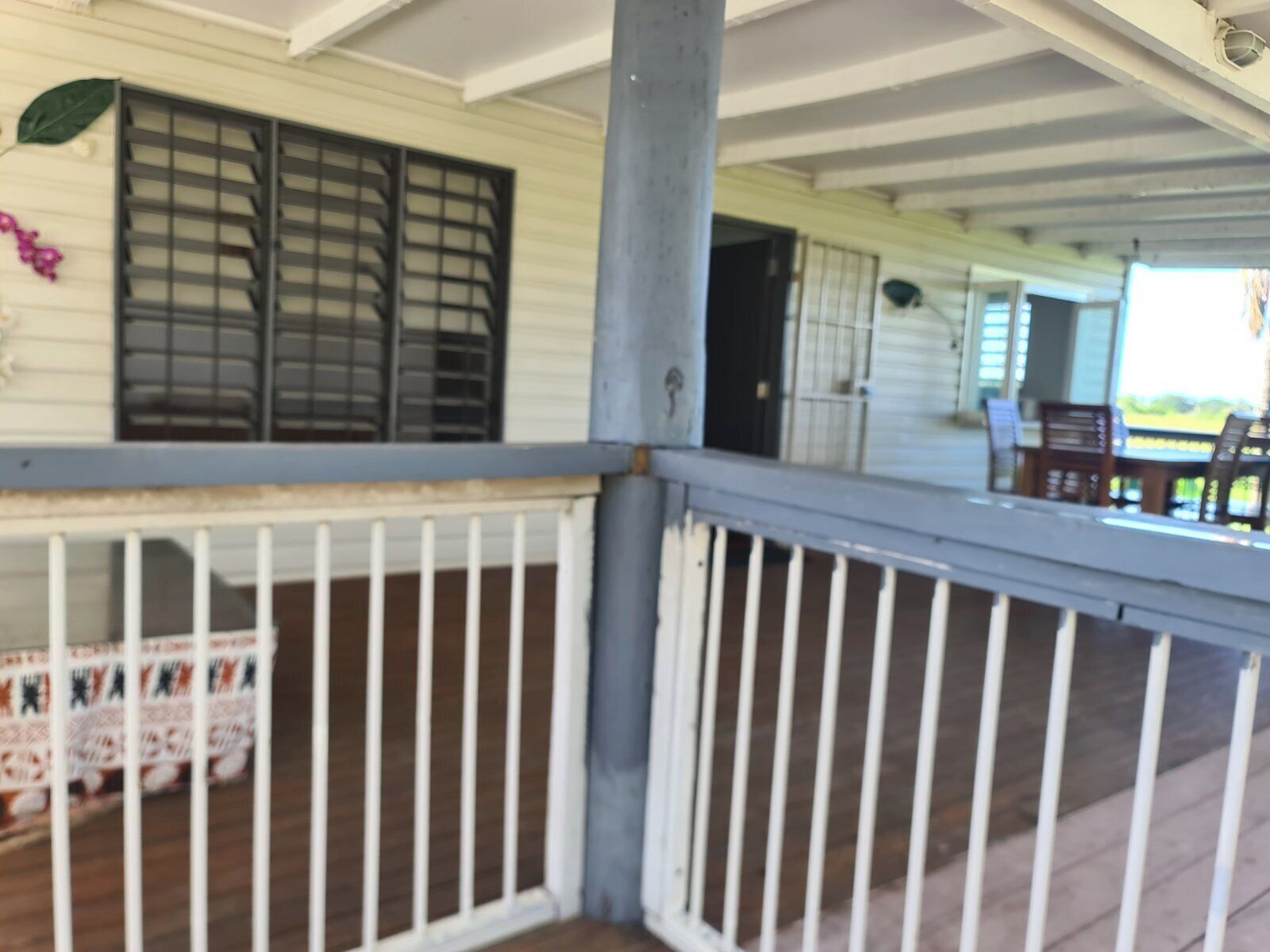 A covered porch with white railings and a wooden deck.