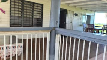 A covered porch with white railings and a wooden deck.