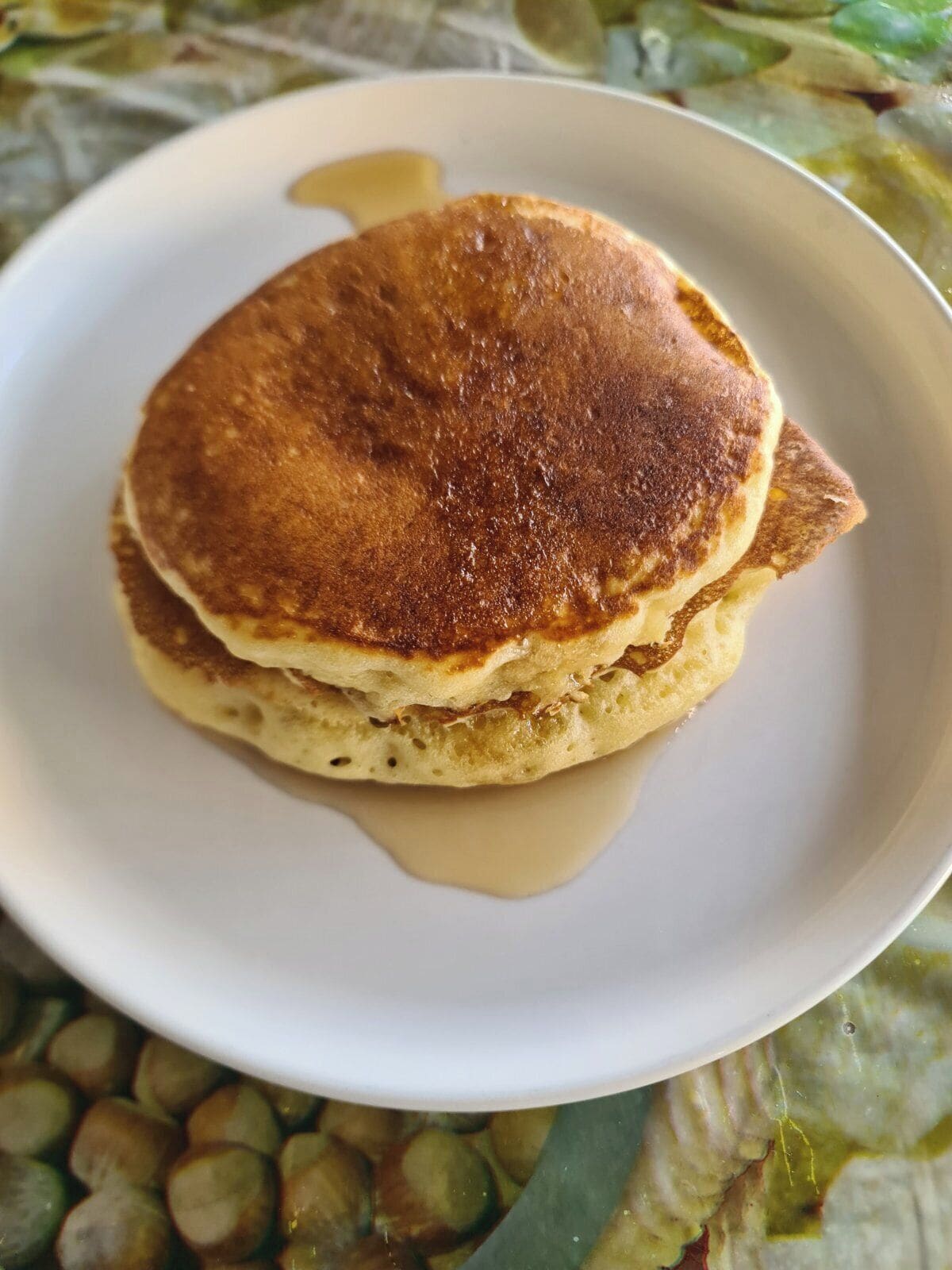 A stack of pancakes with syrup on a white plate.