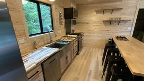 Una cucina moderna con pareti in legno, un lavello in acciaio inossidabile e un tavolo da pranzo in legno con sgabelli da bar.