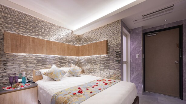 A modern hotel room with a large bed, a wooden nightstand, and a built-in headboard. - hotelbella (Tokyo)