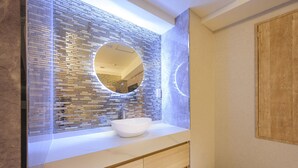 A modern bathroom with a large mirror, a white sink, and a textured wall. - hotelbella (Tokyo)