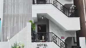 A modern hotel entrance with a staircase, a sign reading "HOTEL Bella," and potted plants. - hotelbella (Tokyo)