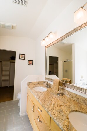 Une salle de bain avec deux lavabos, un grand miroir et un porte-serviettes.