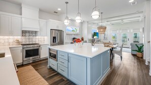 A modern kitchen with white cabinets, stainless steel appliances, and a large island. - Private Pool, Golf Cart Included, Boardwalk to Beach (Port Aransas)