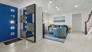 Un salon moderne avec un canapé bleu, une table basse blanche et un tableau représentant des voiliers accroché au mur.