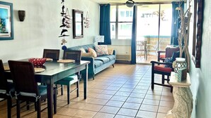 Un espacio habitable amplio con una mesa de comedor, sofás y un ventilador de techo.