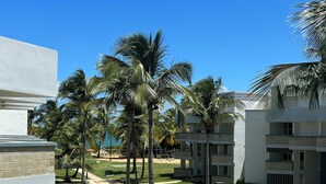 Un hotel moderno con un patio que cuenta con palmeras, una piscina y vistas a la playa.