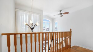 A wooden staircase with a railing leading to a second floor. A ceiling fan is visible in the upper right corner.