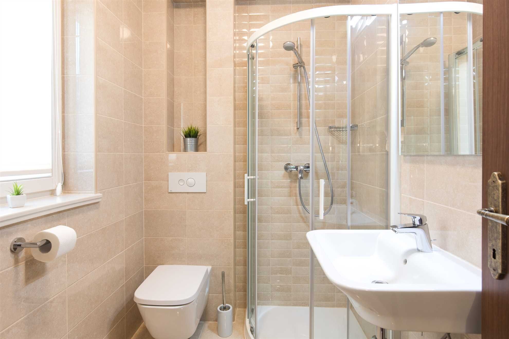 A modern bathroom with a glass-enclosed shower, a white sink, and a toilet.