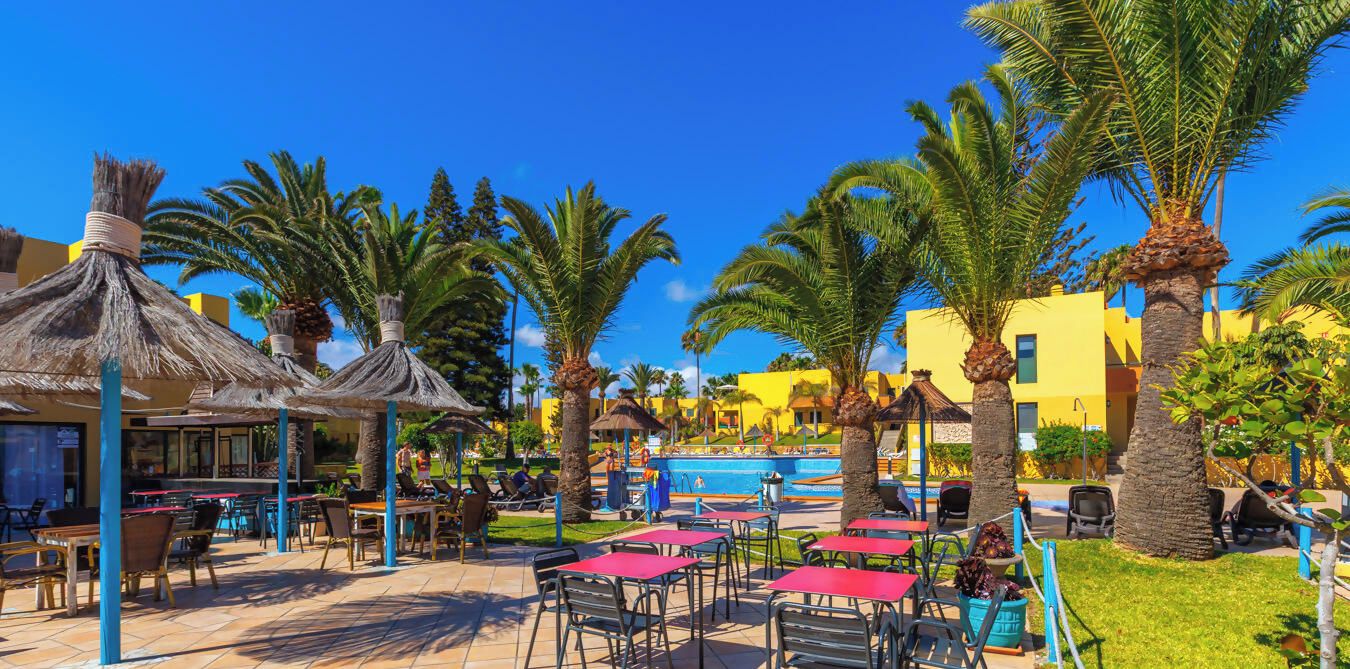 A resort with outdoor seating, palm trees, and a swimming pool.