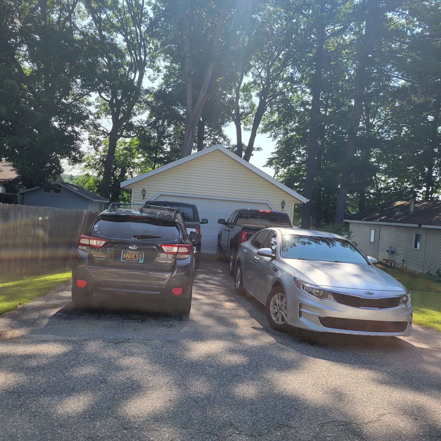 Two cars parked in front of a house with a garage.