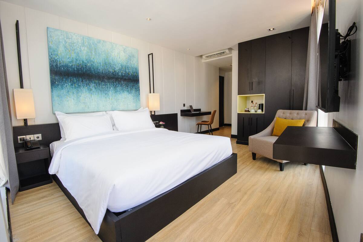 Une chambre d’hôtel moderne, dotée d’un grand lit, d’un bureau, d’une chaise et d’un téléviseur fixé au mur.