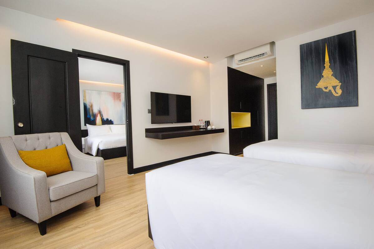 Une chambre d’hôtel avec un lit, un canapé, une télévision et un tableau.