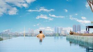 En person slapper af i en stor, indendørs infinitypool med en bys skyline i baggrunden.