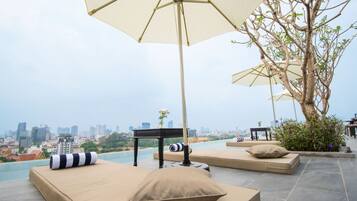 A rooftop lounge with sunbeds, a table, and an umbrella.