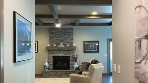 A hallway with a fireplace, a sofa, and framed pictures on the walls. - Luxury Spearfish Retreat-Hot Tub, Fireplace & Gourmet Kitchen-Near Black Hills (Spearfish)