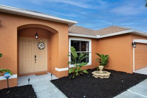Une maison d’habitation avec une porte beige, une fenêtre et une porte de garage.