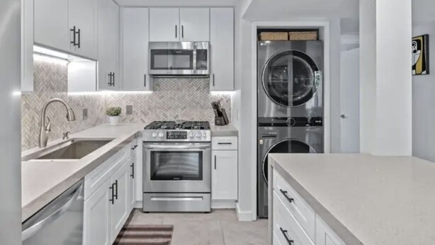 A modern kitchen with white cabinetry, stainless steel appliances, and a built-in washer and dryer. - Great Palm Springs Oasis 2 miles from downtown! (Palm Springs)