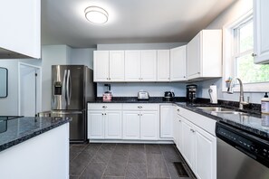 A modern kitchen with white cabinets, stainless steel appliances, and a black granite countertop. - Pet-friendly home near Lake Michigan with fenced in back yard (Benton Harbor)
