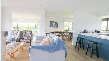 Ein modernes Wohnzimmer mit einer Couch, gemusterten Sesseln, einem Couchtisch und einem Essbereich mit Tisch und Stühlen.