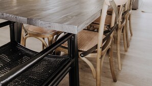 Un vaste espace dédié à la salle à manger, avec une longue table en bois, des chaises confortables et un téléviseur en arrière-plan.