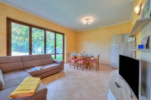 A living room with a sofa, dining table, chairs, and a TV.