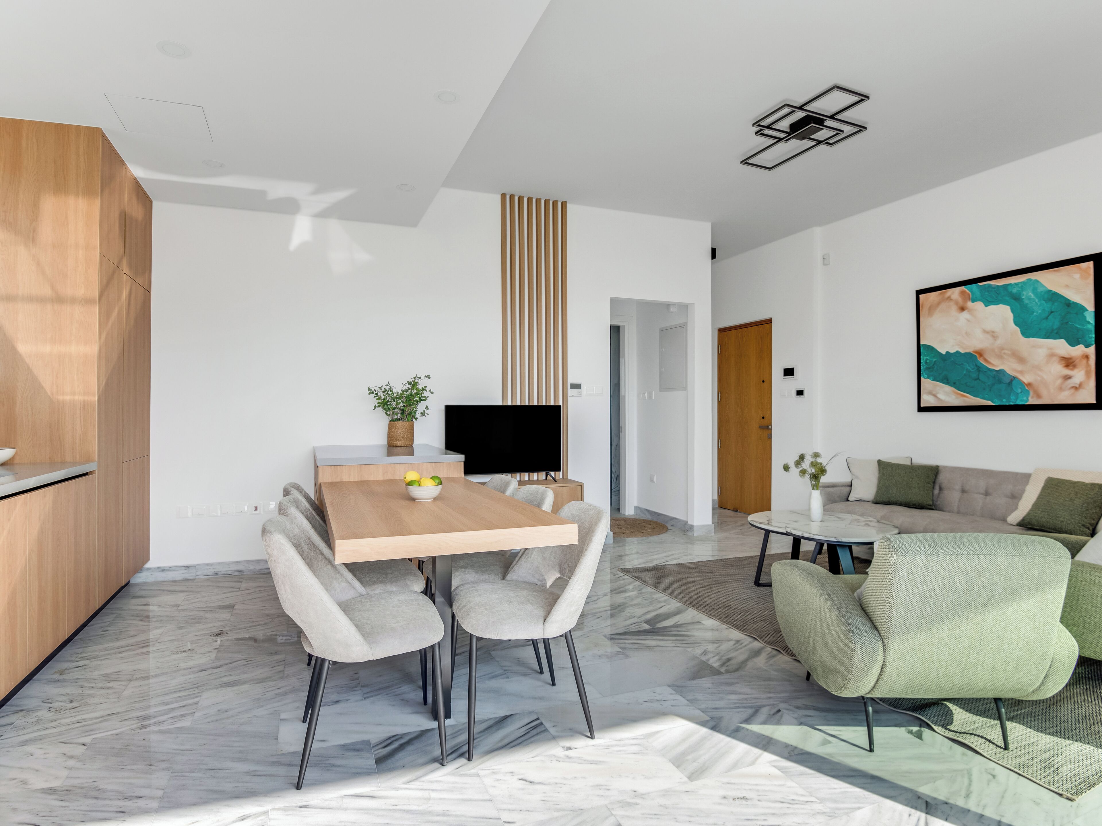 A modern living space with a dining area, a sofa, and a TV.