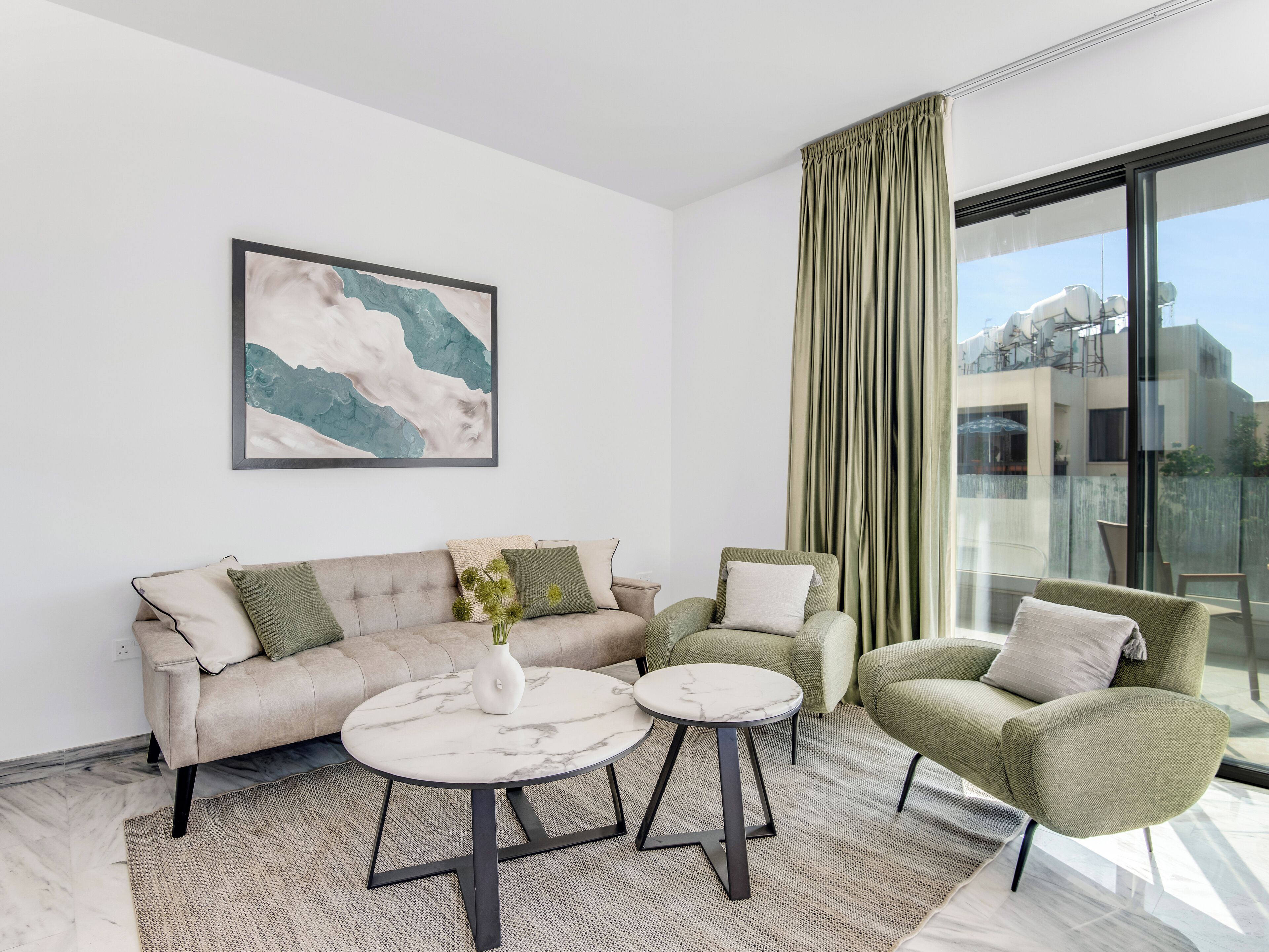 Un salon moderne avec un canapé, deux fauteuils, une table basse et une grande fenêtre avec des rideaux.