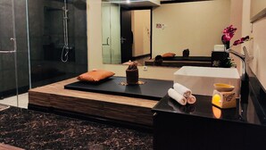 A modern bathroom with a glass shower enclosure, a large mirror, a bathtub, and a vanity with a sink. - Horison Abepura (Jayapura)