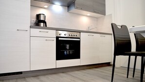 A modern kitchen with white cabinetry, a built-in oven, and a coffee maker. - Panoramic View Apartment Marijane (Preko)