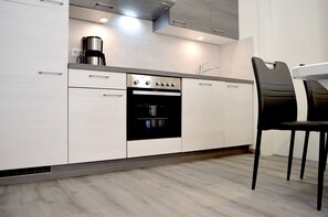 A modern kitchen with white cabinetry, a built-in oven, and a coffee maker.