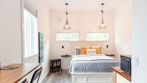 A bedroom with a bed, a desk, a chair, a small table, two pendant lights, and a nightstand. - *Getaway Private Suite "El Faro" (Ucluelet)