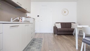 A compact living space with a kitchenette, a sofa, and a dining area. - The House of Corals (Monopoli)