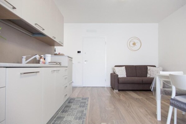 Un espacio habitable compacto con kitchenette, un sofá y una zona de comedor.