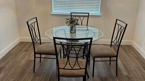 A dining area with a round glass table, four black chairs, a vase with flowers, and a chandelier. - Beautiful and spacious 4BR house in Port St. Lucie, FL (Port St. Lucie)