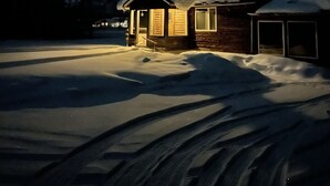Een chalet met een sneeuwbedekte dak en een garage, omgeven door sneeuw.
