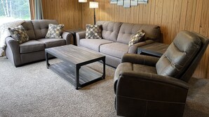 Een moderne woonkamer met een modulaire bank, twee fauteuils, een salontafel en een wandlamp.