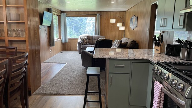 Een moderne keuken met een centraal eiland, houten kasten en een groot raam met uitzicht op de omgeving.
