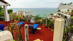 Una escalera conduce a una terraza con mobiliario exterior y vistas al mar.
