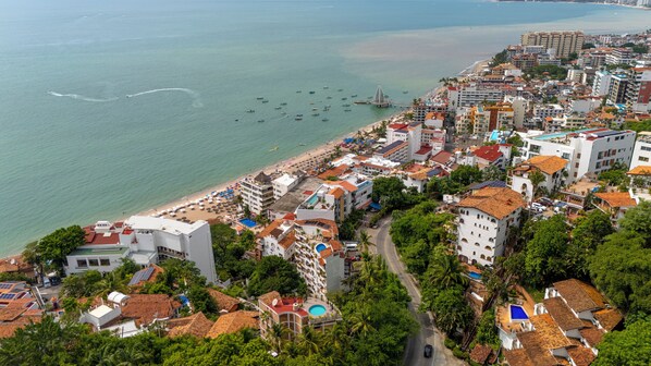 Une ville côtière dotée d’une plage, de bâtiments aux toits recouverts de tuiles rouges et offrant une vue dégagée sur la mer.