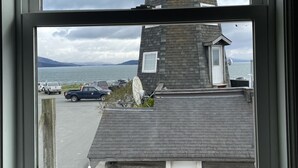 Ein Leuchtturm mit weißer Spitze und grauem Unterteil, sichtbar durch ein Fenster.
