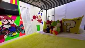 A room with a bed, colorful wall art, and plush toys. - Flamingo  Dream Escape / 5 Bedrooms/ Htd Pool/ Game Room/ BBQ / Baby items (Miami)